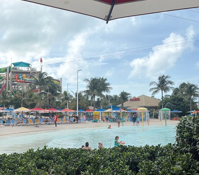 The sloping sandy beach entry into the Thrill Waterpark wave pool at CocoCay, umbrellas and loungers behind.