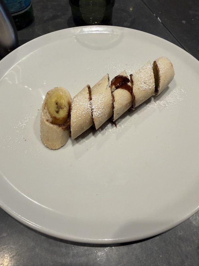 A sliced pastry roll with banana, chocolate sauce and powdered sugar at Giovanni's Kitchen.